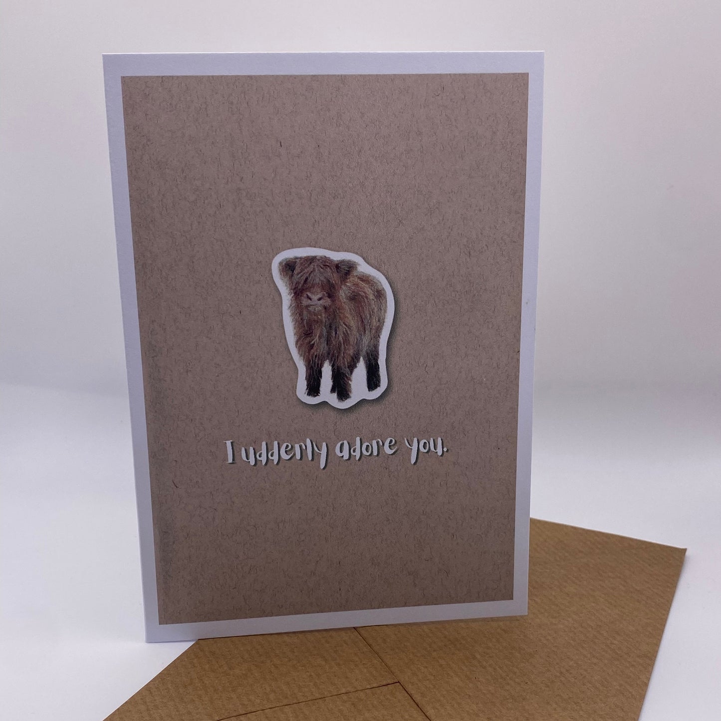 cute pun ainimal greetings card with highland cow calf saying "I udderly adore you" for Valentine's day